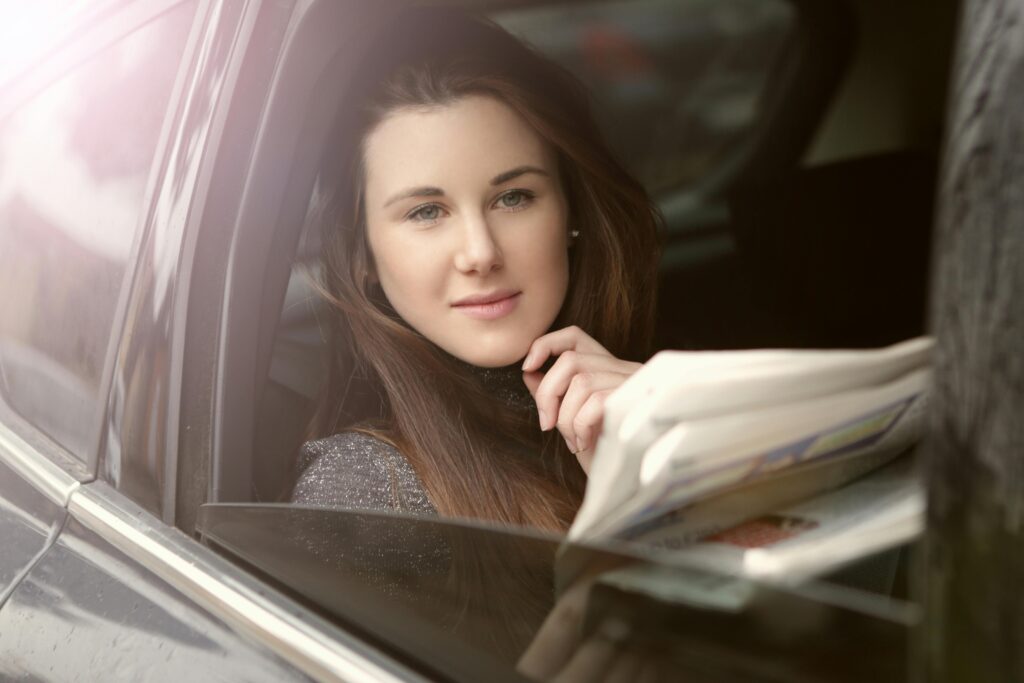 Elegant woman reading in a calm, elegant car interior, showcasing a lifestyle of relaxation.