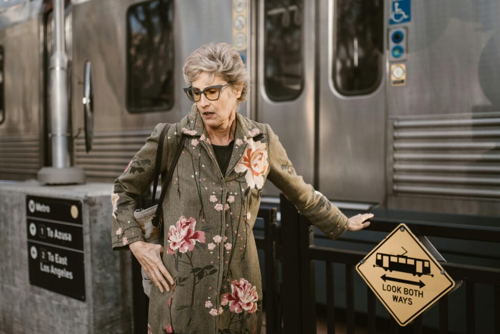 Elegant senior woman in floral coat waiting at Los Angeles metro station.