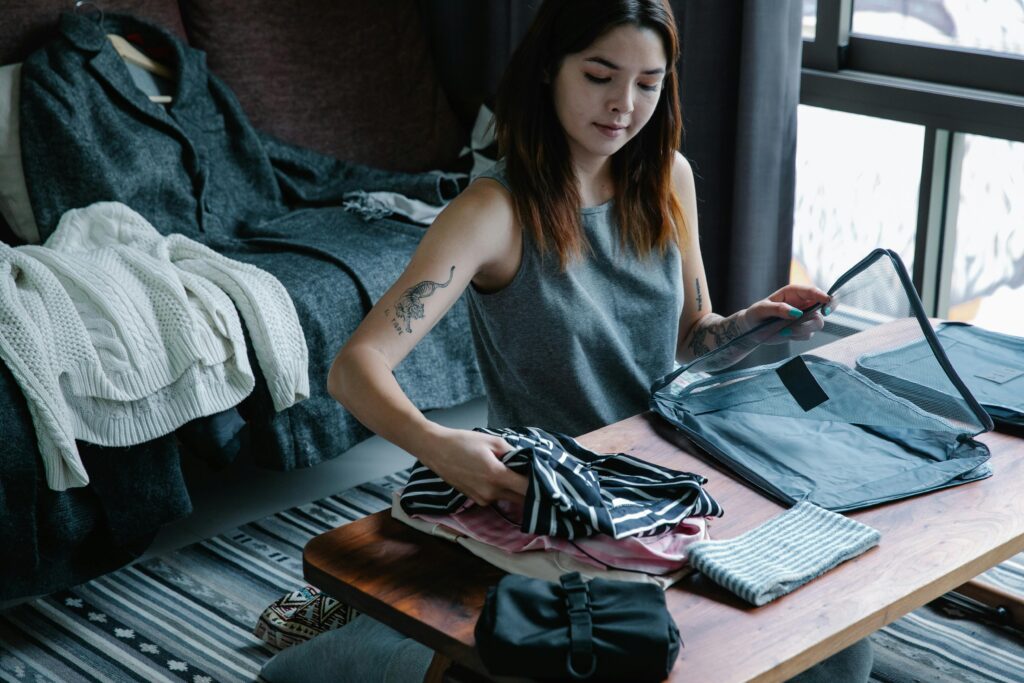 A young woman organizing her clothes in a cozy and modern bedroom, preparing for a trip.